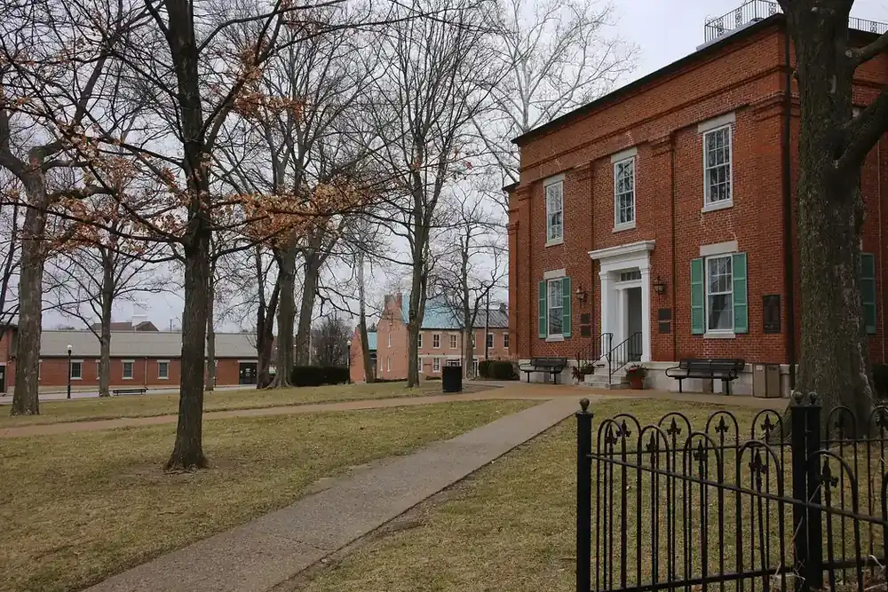 Red brick Monroe County Courthouse with green shutters and bare trees in Waterloo, Illinois